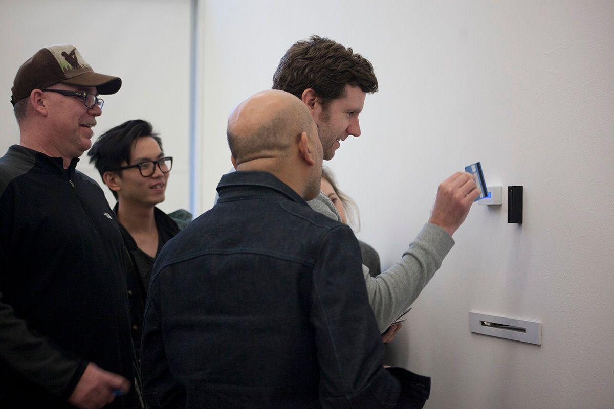 There are five light-skinned people, one with their hand out and a credit card ready to be swiped, in front of the display.