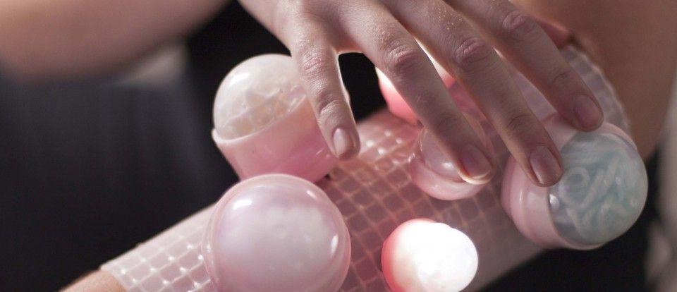 A hand touching a glowing wearable device.