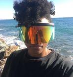 An african american woman on the beach wearing a large colorful mirror shade