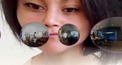 Large distorted woman's head watches over spheres containing different homes.