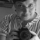 Black and white photograph of a woman holding a camera.