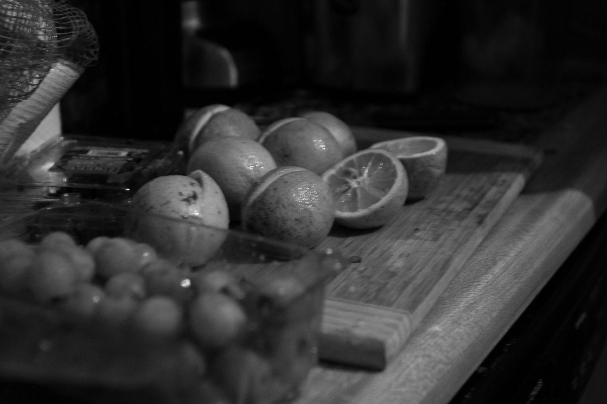 This is a grayscale photo of some lies that are cut in half. In the foreground are some unfocused grapes.