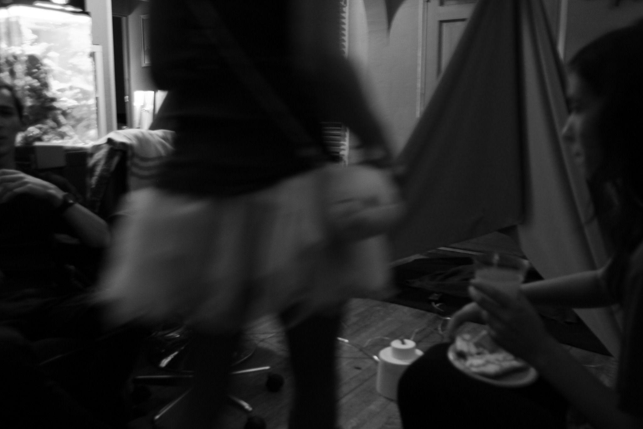 This is a blurry grayscale photo of someone walking in front of the camera. There is a tent inside the room visible in the background.