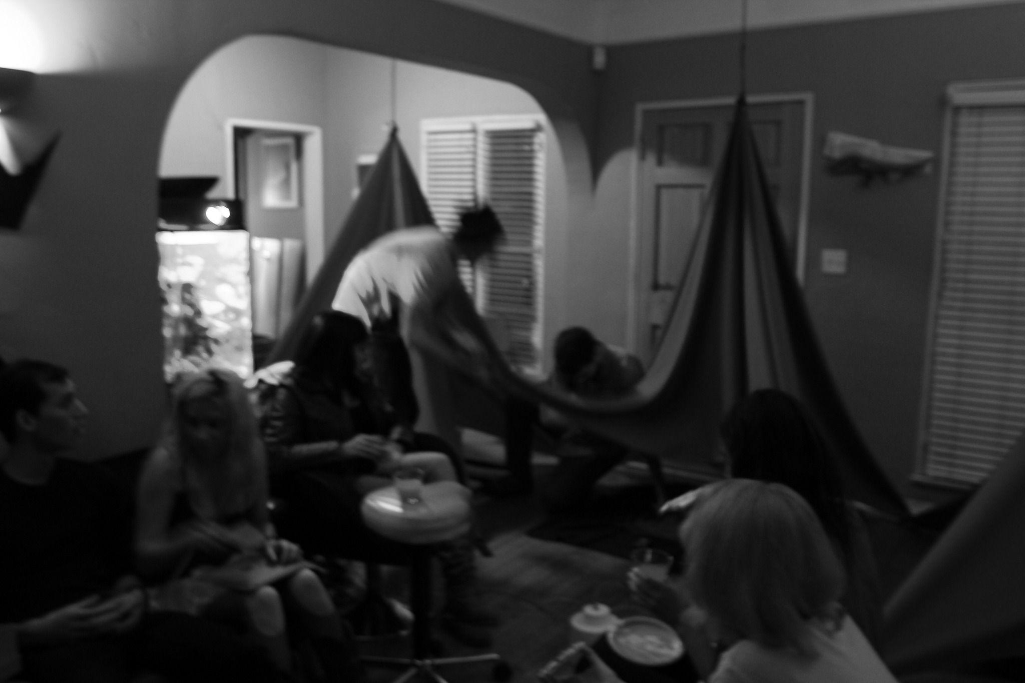 This is a blurry, grayscale photo of people inside a small room sitting and talking to each other. In the background there are two tents.