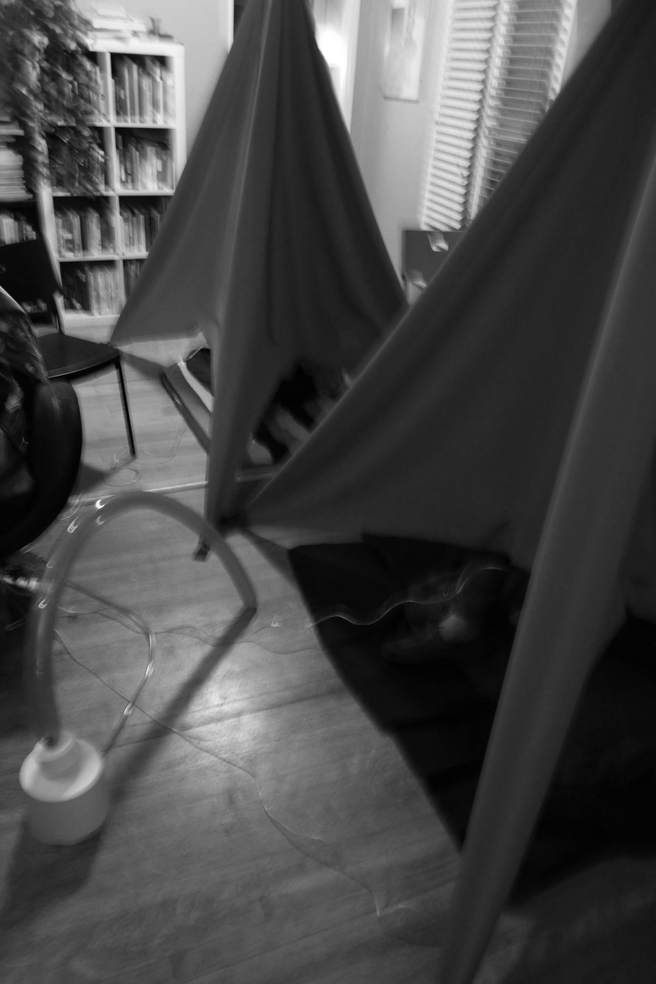 There are two tents inside a small room with a long balloon attached to a white base on the side.